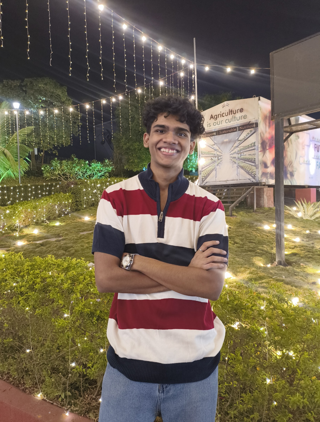 Jaush D'Souza smiling outdoors under string lights